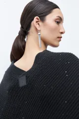 Capa tejida color negro, con cuello redondo, diseño de punto y detalles de lentejuelas. Presenta flecos en el dobladillo.