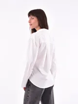 Camisa negra de manga larga con cuello clásico y cierre cruzado con botones.