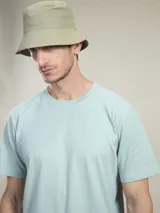 Remera de algodón color verde menta, manga corta y cuello redondo. Estampado grande en la espalda con la palabra "BIOSPHERE" repetida en azul marino y un diseño gráfico de una flor/hojas en amarillo flúor.