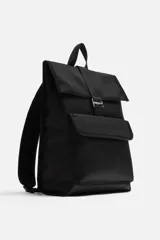 Mochila negra de tejido técnico con solapa y hebilla. Tiene un bolsillo frontal, un bolsillo interior con cierre y un compartimento para dispositivos electrónicos de hasta 13 pulgadas. La parte posterior es acolchada y tiene una banda de sujeción para equipaje.