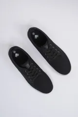 Zapatillas acordonadas de lona negra con suela blanca y detalle de línea negra en el borde superior.