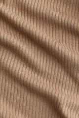 Pantalón largo color beige de punto acanalado con cintura elástica y corte ajustado hasta la rodilla, con terminación acampanada.