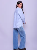 Camisa celeste a rayas verticales con cuello mao y cierre frontal con botones.