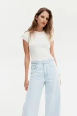 Remera blanca de punto acanalado fino, con cuello redondo y mangas cortas con ribete de encaje.