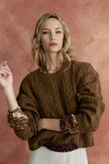 Sweater marrón de punto trenzado con cuello redondo y mangas largas.