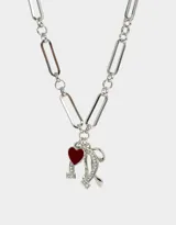Collar corto plateado con cadena de eslabones grandes y dijes colgantes de moño, corazón rojo y herradura con strass.