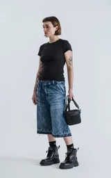 Bermuda larga de denim con calce oversize, desgaste y ruedo desflecado.