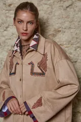 Camisa beige de simil gamuza, calce holgado, manga ancha con bordado de serpiente en el canesú y detalles en las mangas.