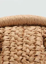 Bolso de mano tipo clutch color beige, tejido en fibra natural. Tiene asa larga desmontable para usar como bandolera, cierre a presión y forro interior.