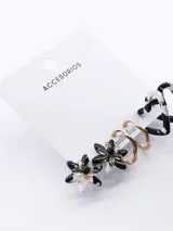 Set de tres pares de aros con diferentes diseños: aros tipo botón con forma de flor en blanco y negro, aros colgantes dorados con forma de onda y aros tipo argolla con estampado abstracto en blanco y negro.