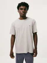 Pijama gris compuesto por una remera de manga corta con cuello redondo y un pantalón largo. La remera tiene un pequeño bordado en el pecho.