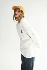 Buzo blanco de algodón con costuras a contratono, ruedo al corte y parche con logo en el pecho.