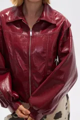 Chaqueta de eco-cuero color bordó, holgada, con cierre frontal, cuello tipo camisa y bolsillos laterales.