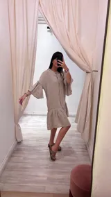 Vestido corto color beige, de lino, con cuello mao, botones de nácar, mangas 3/4 con volados y falda con volados.