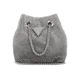 Cartera tipo bucket de Guess, color plateado con apliques de strass. Tiene asa de cadena y logo triangular metálico en el frente.