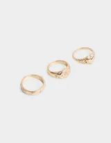 Set de tres anillos dorados con diferentes diseños: uno con forma de corazón, otro con flores rosas y otro con diseño de soles.