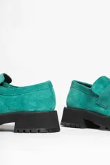 Mocasín de gamuza color verde oliva, con tira superior y suela track gruesa y negra.