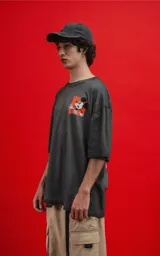 Remera de algodón premium, color gris oscuro con efecto lavado, corte oversize y manga corta. Presenta un pequeño estampado frontal de Mickey Mouse en un recuadro naranja.