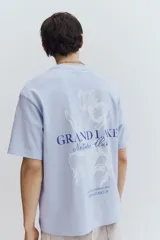 Remera celeste de corte holgado con cuello redondo y estampado frontal con la frase "Grand Lake Nature Club".