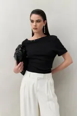 Top tejido azul marino de silueta ajustada con diseño minimalista y escote asimétrico, adornado con pequeños botones metálicos.
