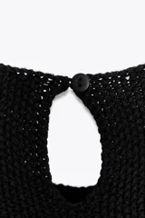 Vestido corto de punto negro con panel lateral color crema, de cuello redondo y sin mangas.