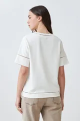 Remera blanca de manga corta con cuello redondo y detalle de vainillas en cuello, mangas y centro.