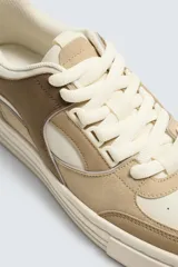 Zapatillas deportivas de estilo retro, color beige y marrón, con cordones y suela gruesa.