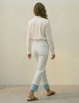 Jean de algodón de tiro medio, color celeste muy claro, con un dobladillo ancho y contrastante en color azul claro en los tobillos. El corte es recto o ligeramente holgado.