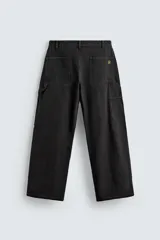 Pantalón negro de corte amplio, confeccionado en tejido de algodón con efecto lavado. Presenta bolsillos frontales, traseros de parche, tira multifunción y bolsillos laterales en las perneras. Cuenta con cierre frontal con cremallera y botón.