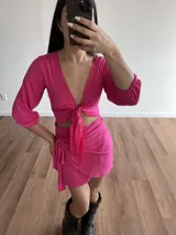 Conjunto de top manga larga con nudo frontal y falda corta cruzada con lazo lateral, color fucsia.