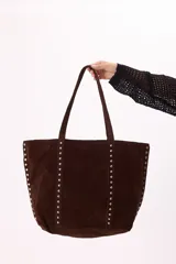 Bolso tote marrón de gamuza sintética con tachas metálicas plateadas en los bordes y asas de hombro.