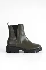 Bota Chelsea color verde oliva de cuero, con elásticos laterales negros, tirador trasero y suela track negra.