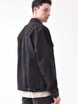 Campera de jean negra con botones metálicos, bolsillos frontales con solapa y cuello clásico.