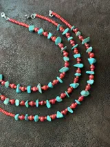Collar corto con cuentas de coral natural color rojo, escallones turquesas y mostacillas. Se cierra con cadena de acero quirúrgico y ganchito para regular el largo.