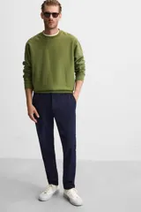 Pantalón negro de corte slim fit, confeccionado en tejido elástico. Cuenta con cintura elástica, bolsillos frontales y traseros de vivo. Cierre frontal con cremallera y botón.