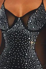 Vestido corto negro ajustado al cuerpo, con breteles finos y escote en V. Presenta detalles de strass plateados en el busto y en todo el frente. Tiene paneles de tul transparente en los laterales.