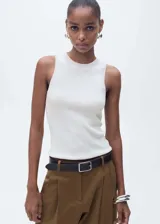 Musculosa blanca de tejido de punto fino, cuello redondo, tirantes anchos y diseño entallado.