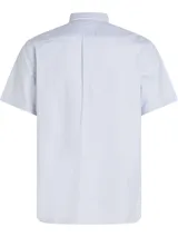 Camisa de manga corta Tommy Hilfiger Heritage, de corte regular, confeccionada en tela Oxford a rayas verticales celestes y blancas. Tiene cuello abotonado, cierre con botones y logo de Tommy Hilfiger bordado en el pecho.