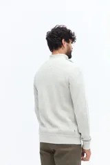 Buzo de algodón color verde musgo, con cuello alto y cierre frontal parcial. Presenta puños y cintura acanalados, y un pequeño logo bordado en el pecho.