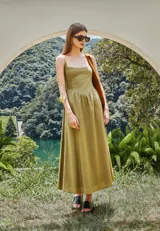 Vestido midi de lino y viscosa color beige claro, con escote cuadrado y breteles finos. Presenta un detalle de punto smock en la espalda y bolsillos laterales.