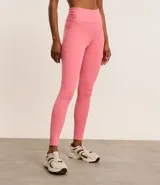 Calza deportiva larga color rosa, confeccionada en microfibra, con cintura alta con elástico porta remera y bolsillo lateral.