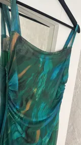 Vestido largo ajustado al cuerpo, confeccionado en microtul estampado con diseño abstracto en tonos verde, azul y marrón. Tiene breteles finos y forro interior opaco.