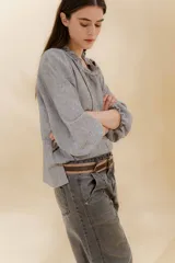 Blusa color beige con cuello mao con volantes, manga larga con puño elástico y cierre frontal con botones ocultos.