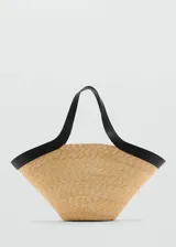 Bolso tipo shopper de paja color beige con ribete y asas cortas de cuero sintético negro.