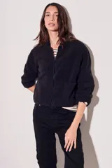 Campera de forro polar negra, con cierre frontal y bolsillos, diseño ligero y al cuerpo.
