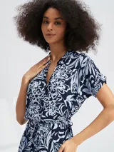 Vestido corto con estampado floral en tonos azul y blanco, con cuello en V, mangas cortas y lazo en la cintura.