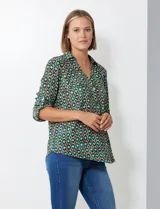 Blusa de gasa con estampado geométrico en tonos verdes, azules y morados. Presenta cuello con solapa, escote en V con botones y mangas largas que se pueden remangar y sujetar con presilla.