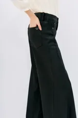 Pantalón de jean negro de corte oxford, tiro medio, con cintura y cadera ajustadas, y piernas anchas con recortes laterales.
