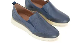 Zapato tipo mocasín color azul marino, con elástico en la abertura y suela color crema.