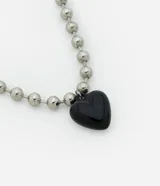 Collar corto con cadena de bolitas plateadas y dije de corazón negro.